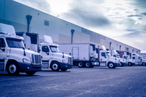 White semi trucks backed into bays at a warehouse where loading or unloading of freight will occur